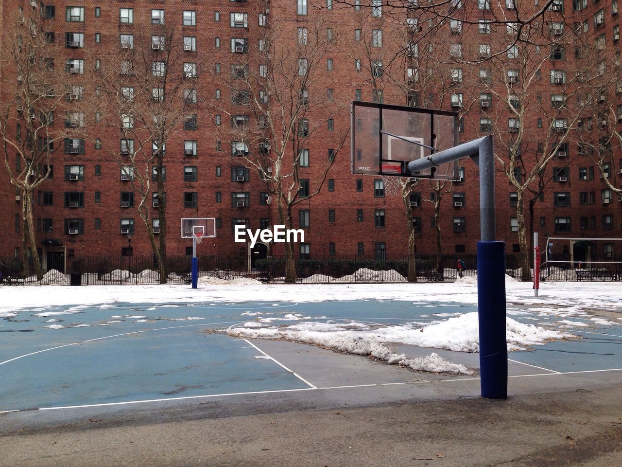 Empty basketball court against buildings in winter