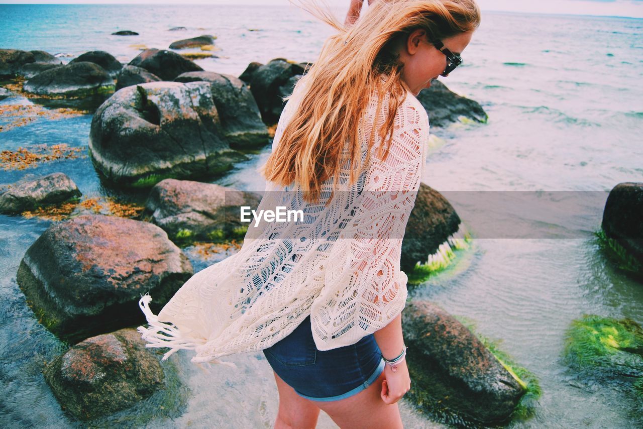 Young woman looking down while standing at beach