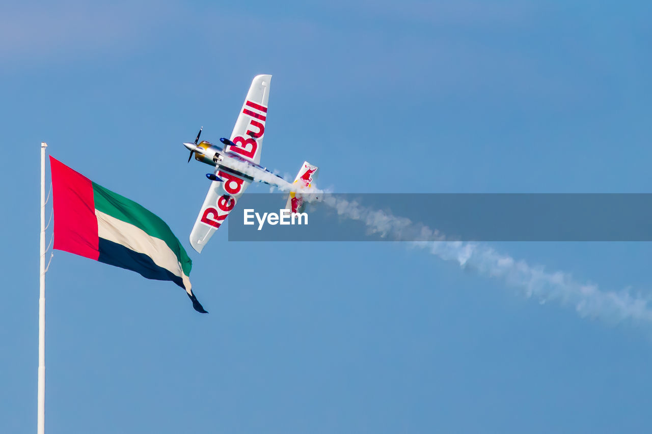 LOW ANGLE VIEW OF FLAG FLYING AGAINST BLUE SKY