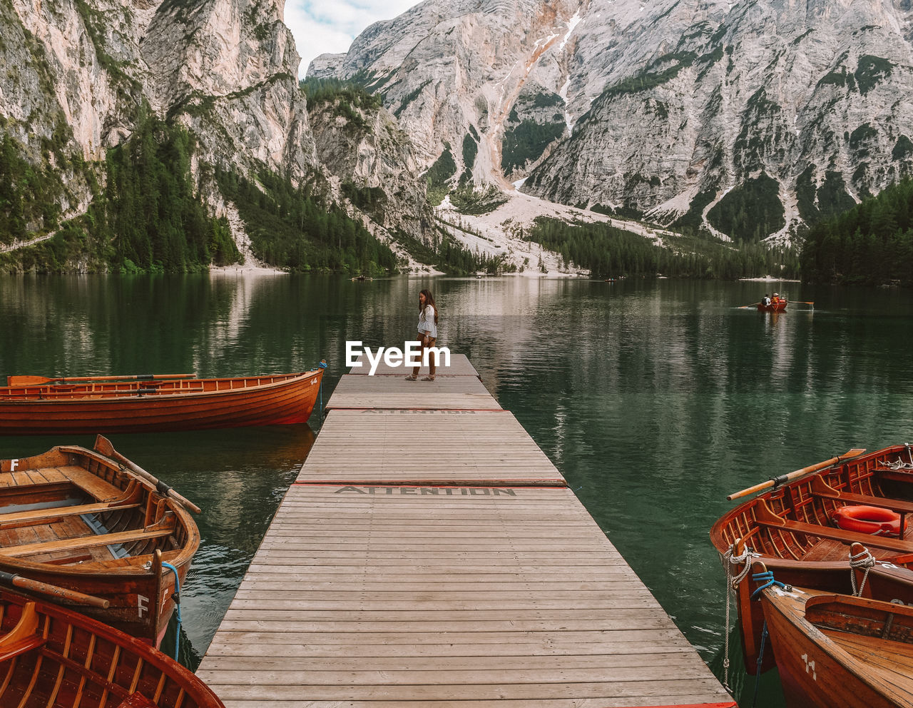 Woman standing on pier over lake against mountains