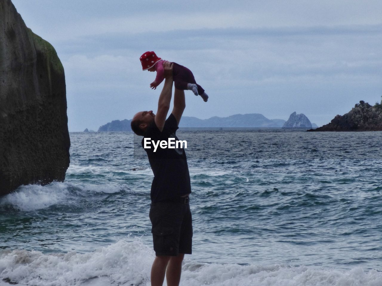 Side view of man playing with daughter at beach 