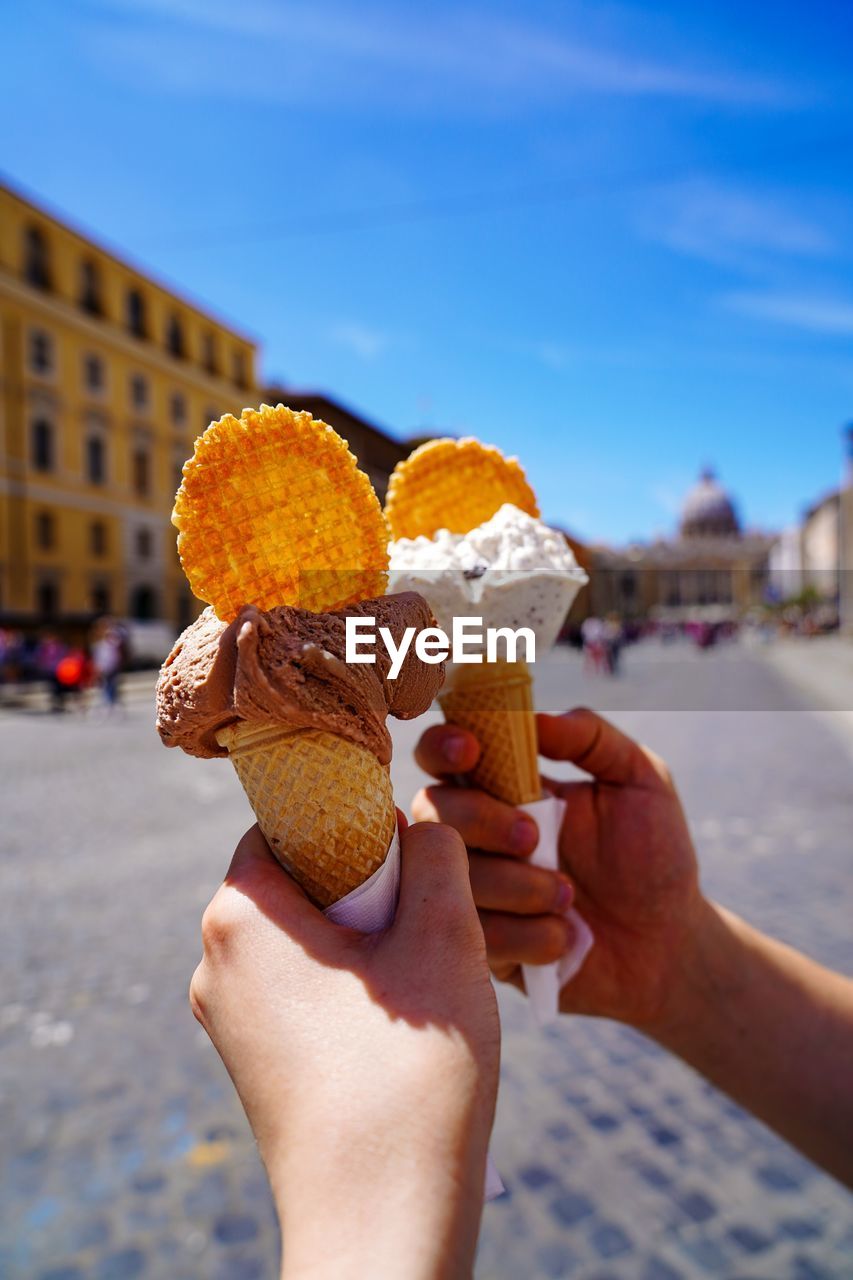 Two hands holding ice cream cone in the sun