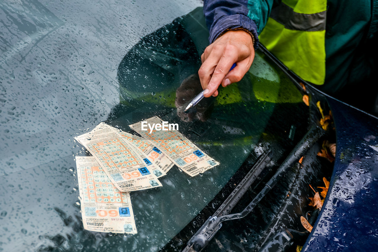 HIGH ANGLE VIEW OF MAN HOLDING UMBRELLA ON WET STREET