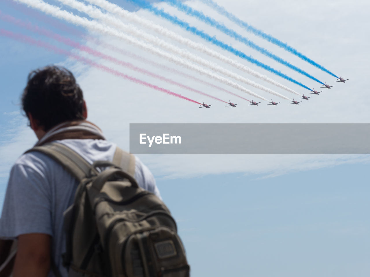 REAR VIEW OF MAN FLYING AGAINST AIRPLANE SKY