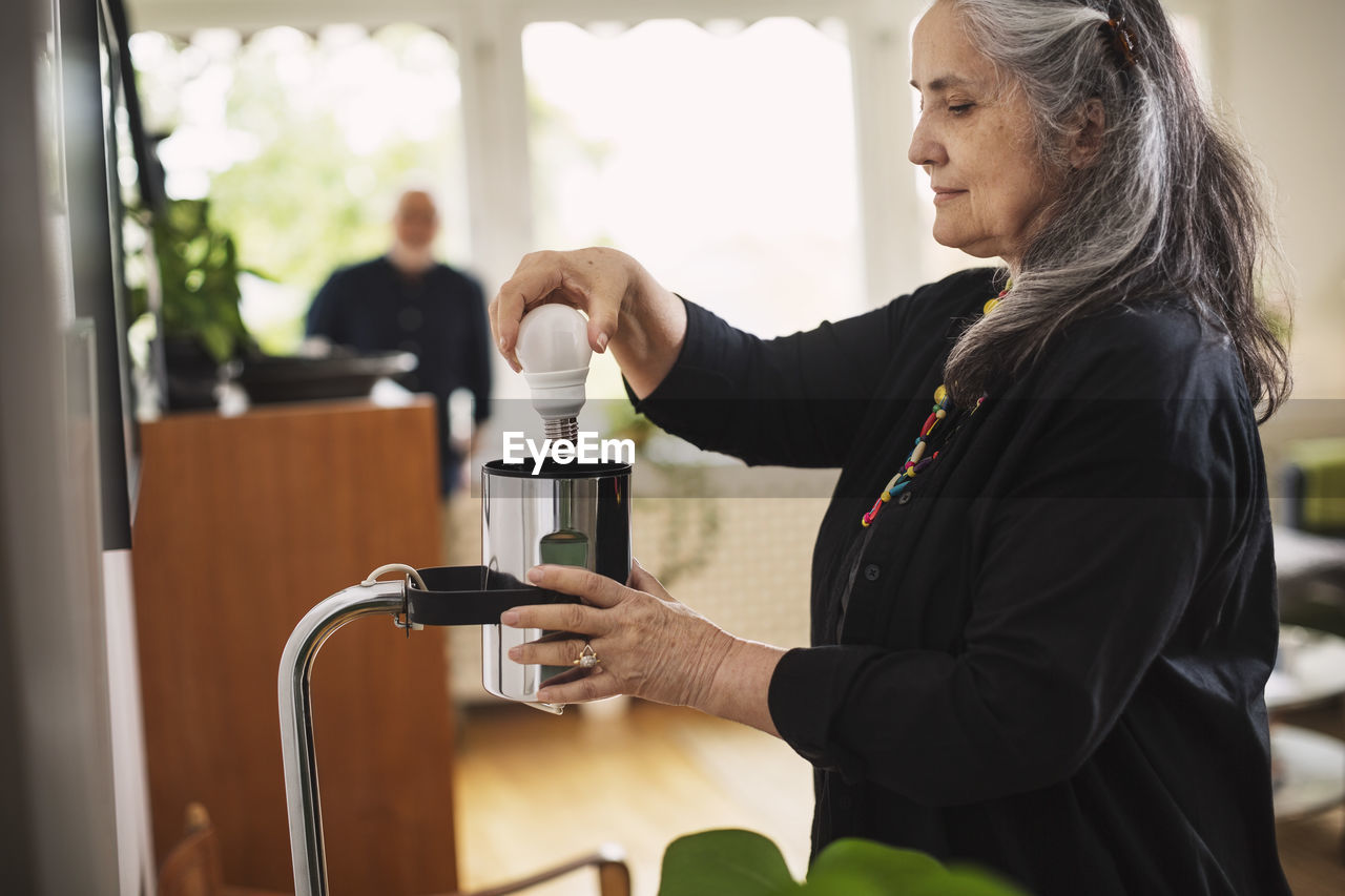 Senior woman changing bulb at home