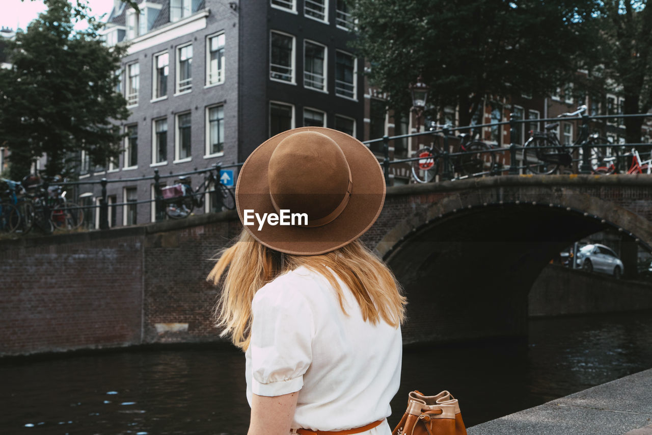 Woman sitting on canal in city