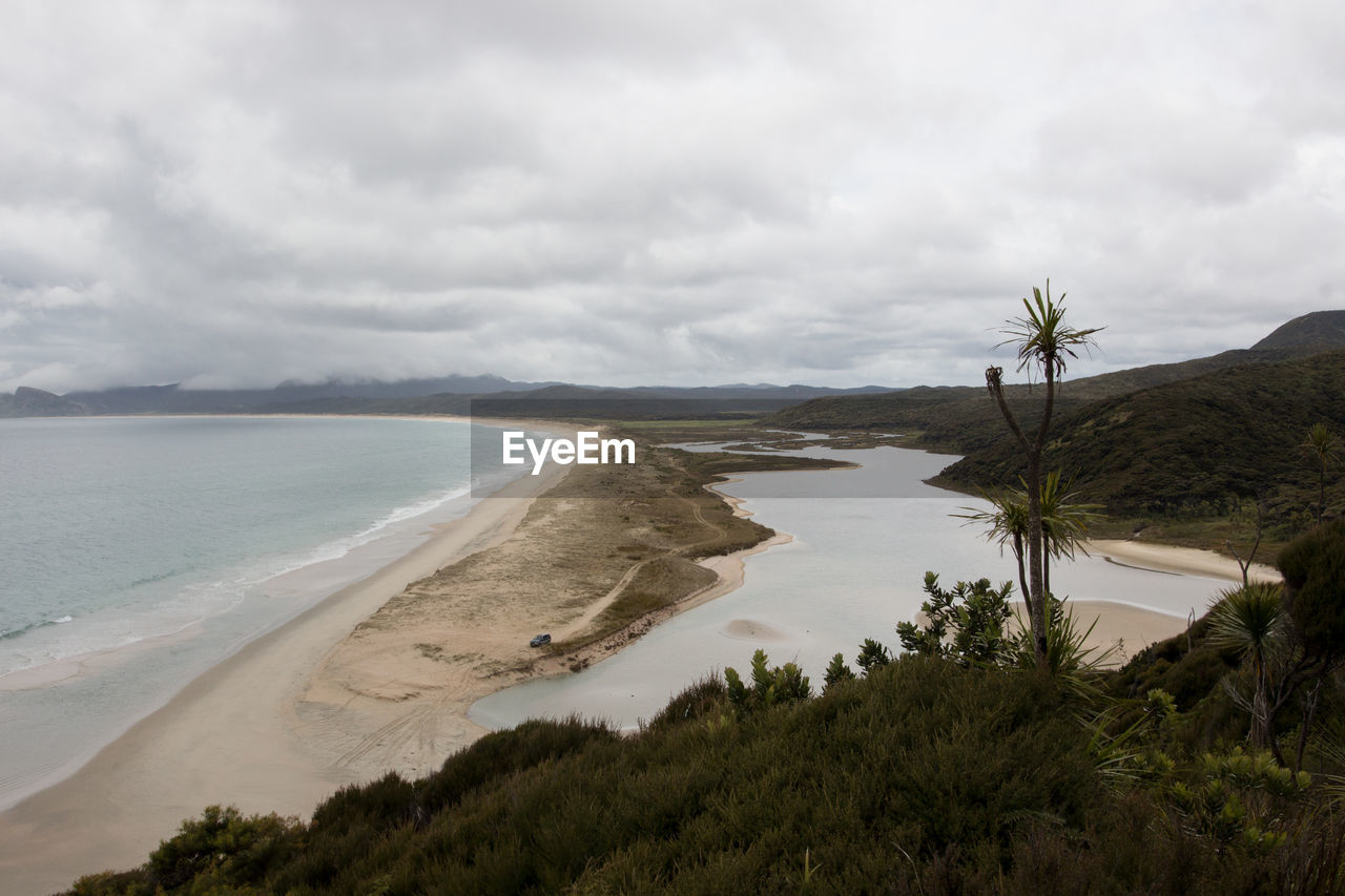 SCENIC VIEW OF BEACH AGAINST CLOUDY SKY