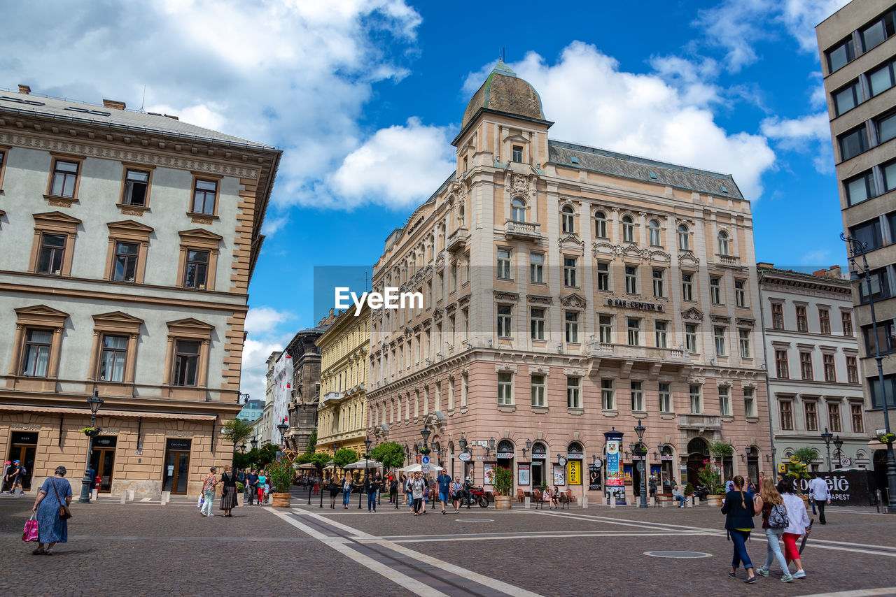 GROUP OF PEOPLE WALKING IN FRONT OF BUILDING