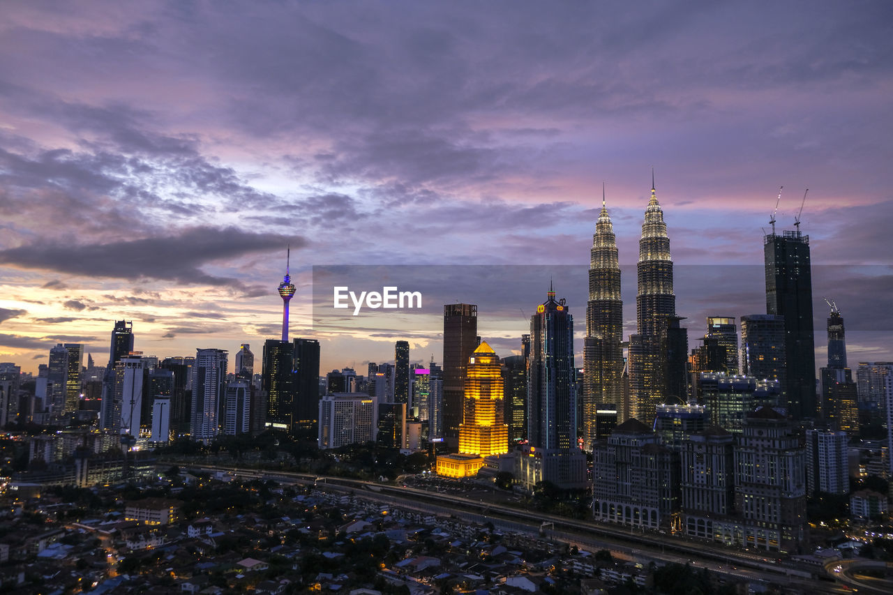 Illuminated cityscape against sky during sunset