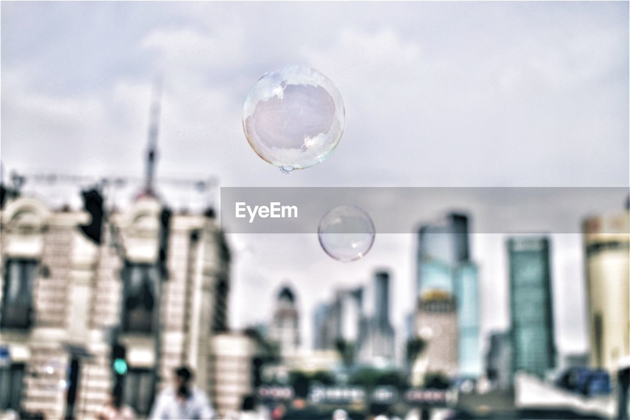 Bubbles against buildings in city against sky