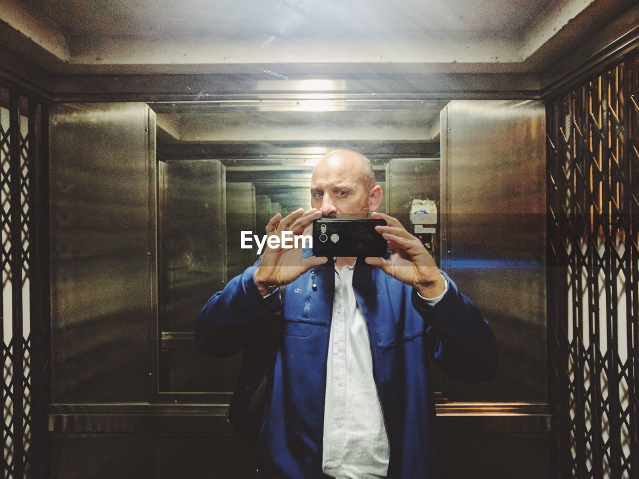 Man taking selfie of reflection in elevator