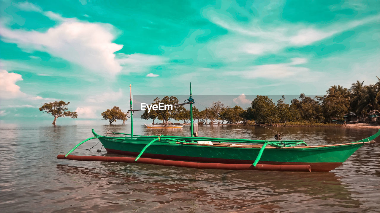 BOATS MOORED ON SHORE AGAINST SKY