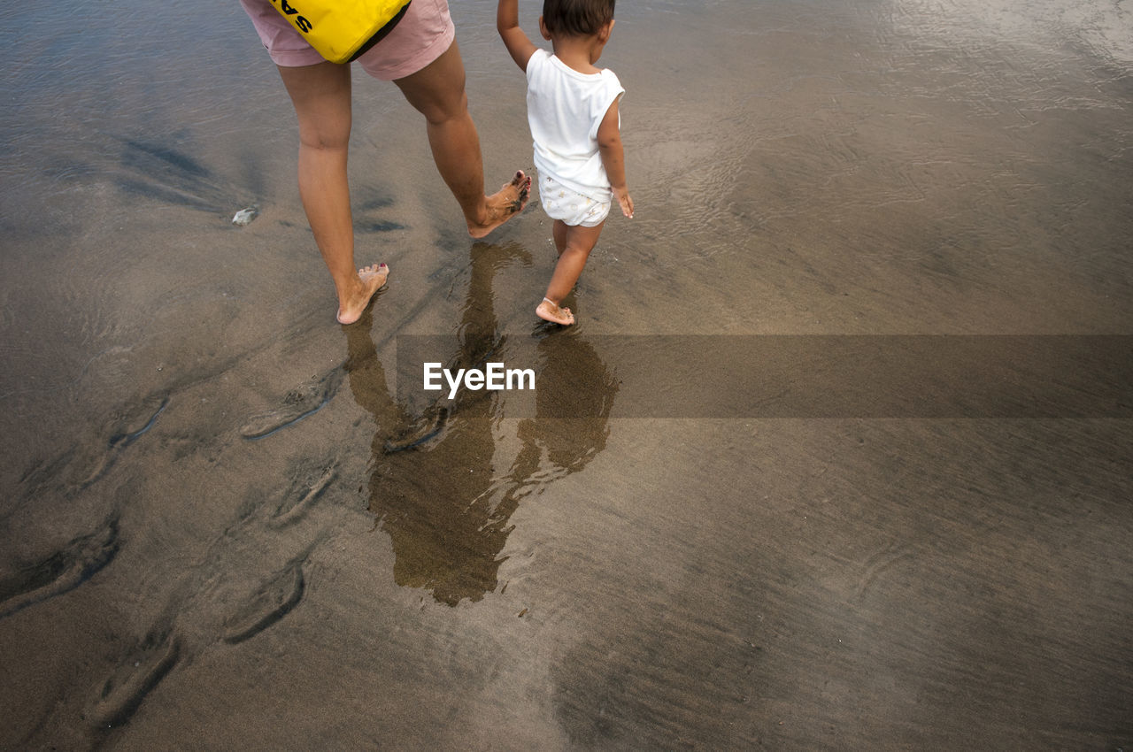 High angle view of mother walking with son on shore