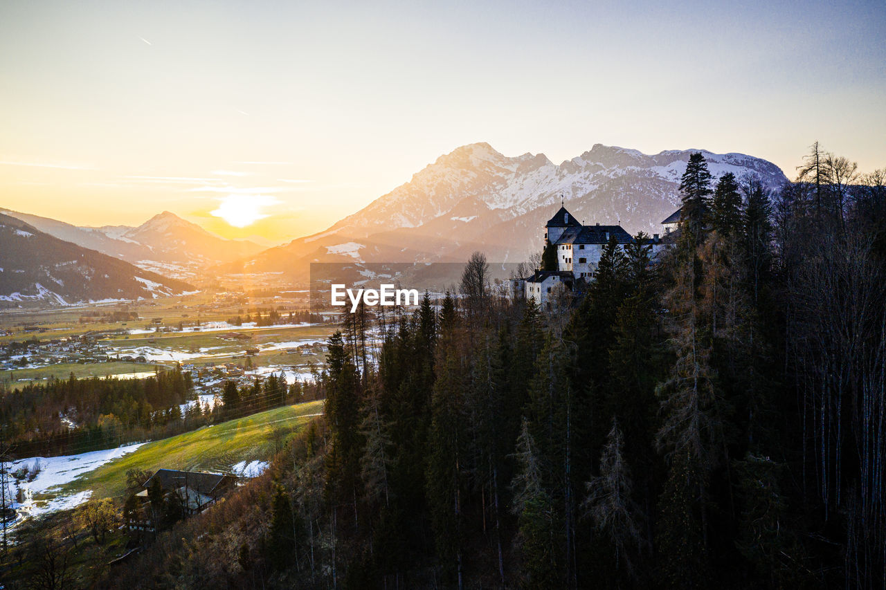 Scenic view of snowcapped mountains against sky during sunset with a castle in the voreground