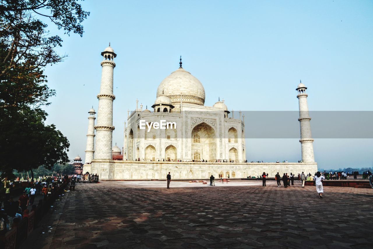 GROUP OF PEOPLE IN FRONT OF HISTORICAL BUILDING AGAINST CLEAR SKY