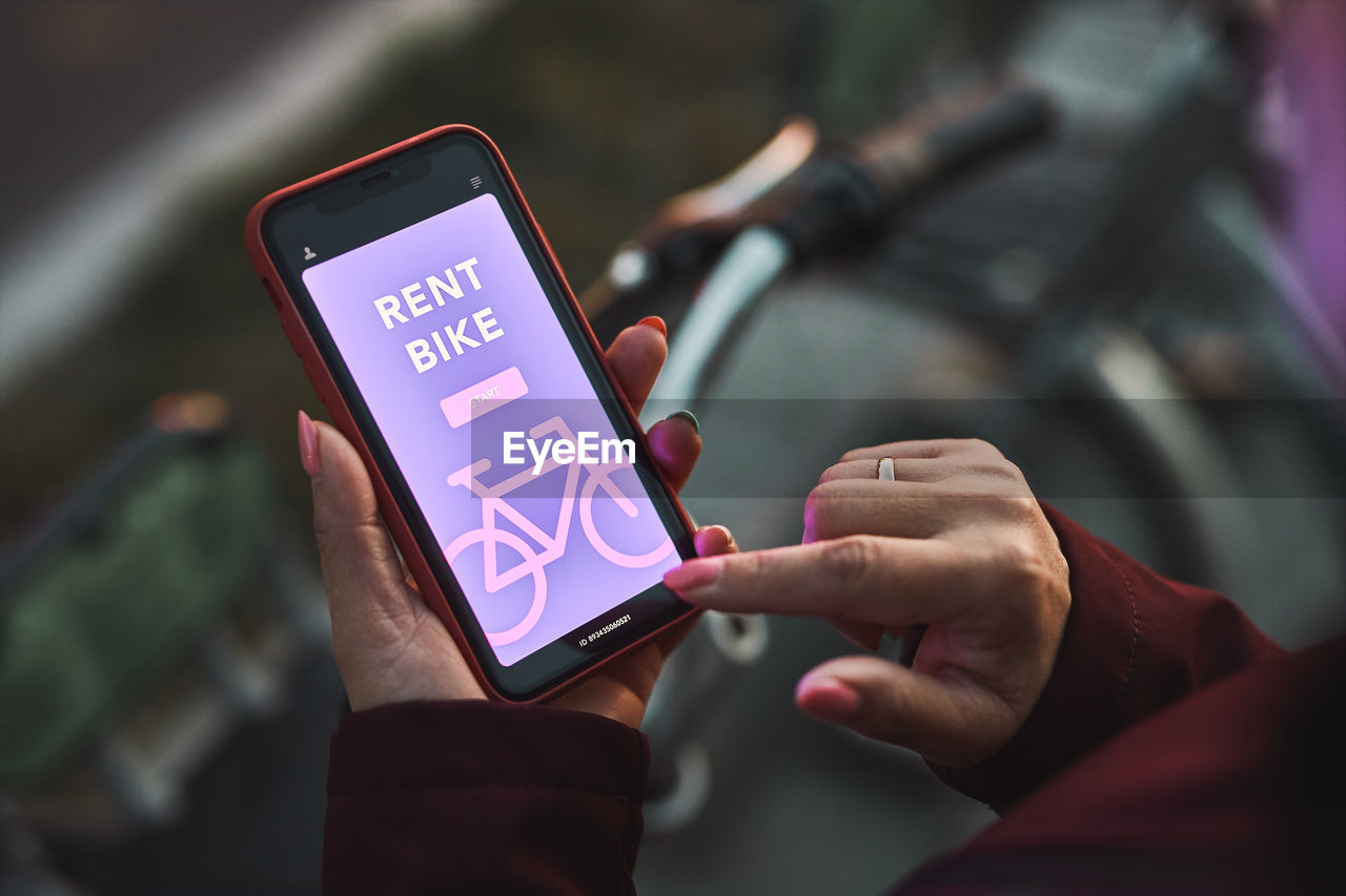 Woman renting bike using rental app on mobile phone. using bike sharing city service. mobile app