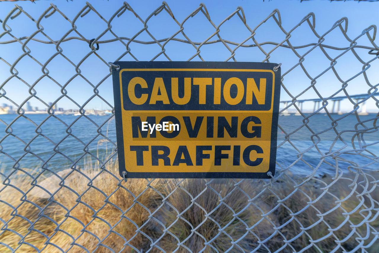 WARNING SIGN ON CHAINLINK FENCE AGAINST METAL