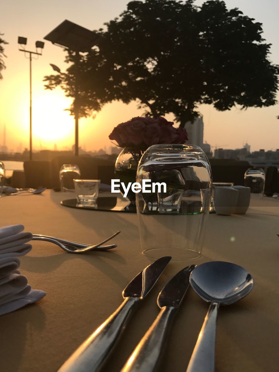 PEOPLE SITTING ON CHAIR AT TABLE AGAINST SUNSET