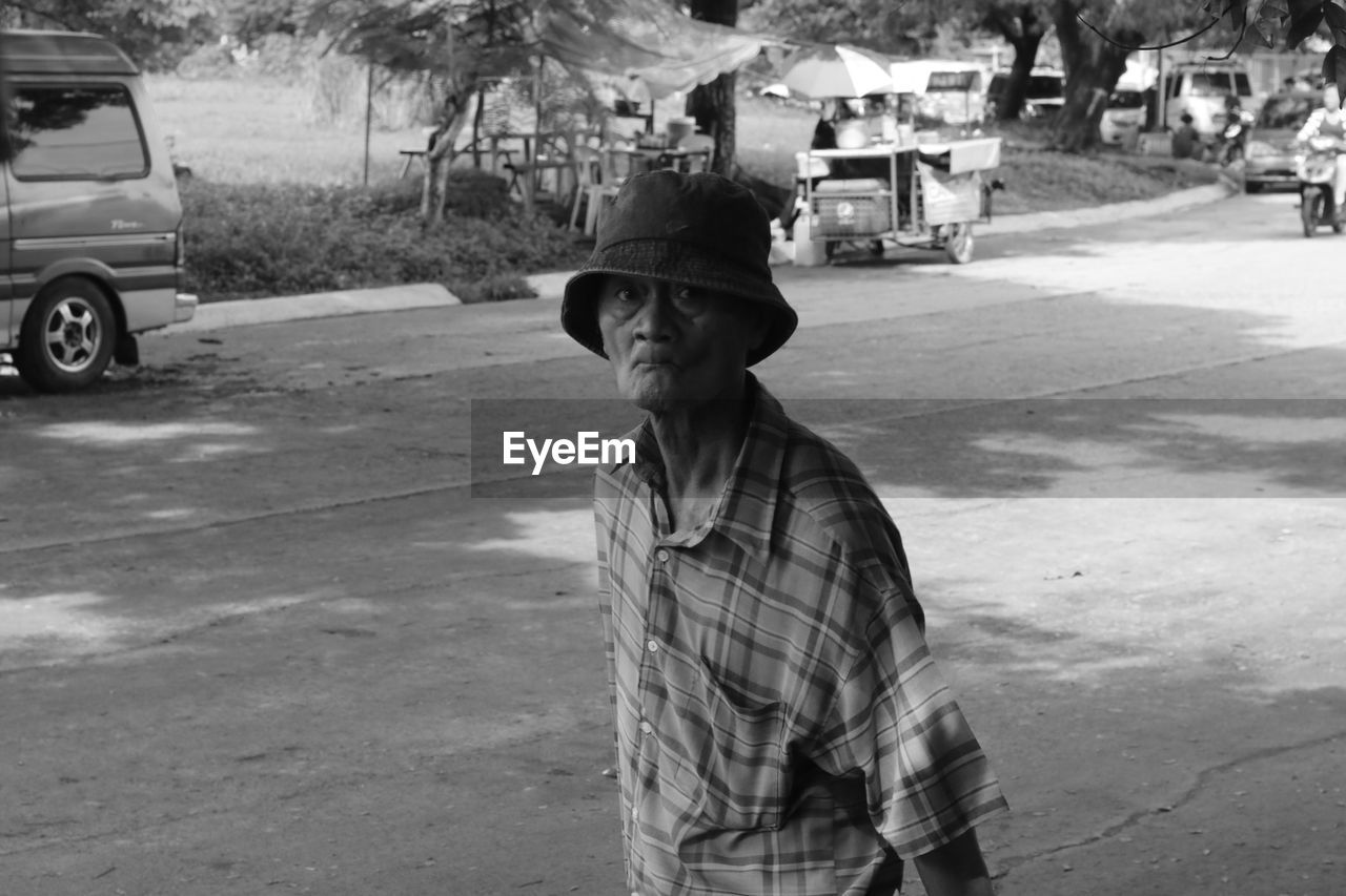 road, black and white, transportation, street, one person, men, monochrome photography, monochrome, mode of transportation, adult, day, black, car, infrastructure, land vehicle, hat, city, vehicle, lifestyles, motor vehicle, white, clothing, nature, casual clothing, tree, outdoors, senior adult, occupation, person, plant, leisure activity, standing