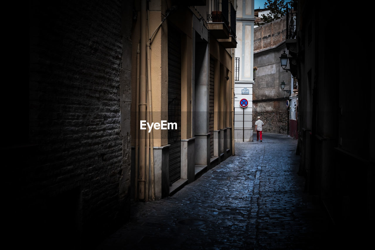 Man walking in alley amidst buildings