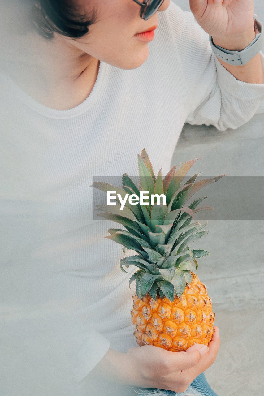 Midsection of woman holding pineapple