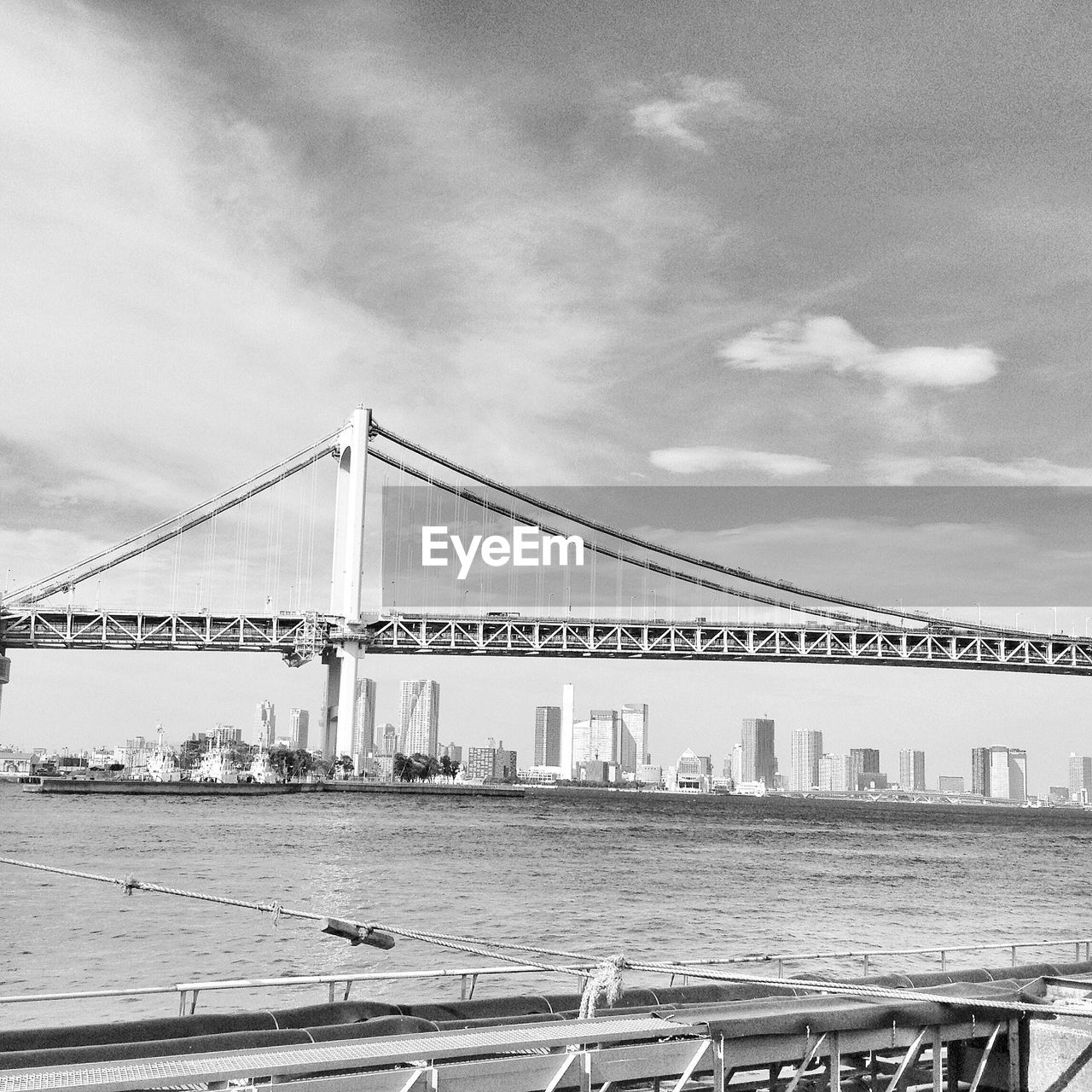Suspension bridge over river against cloudy sky
