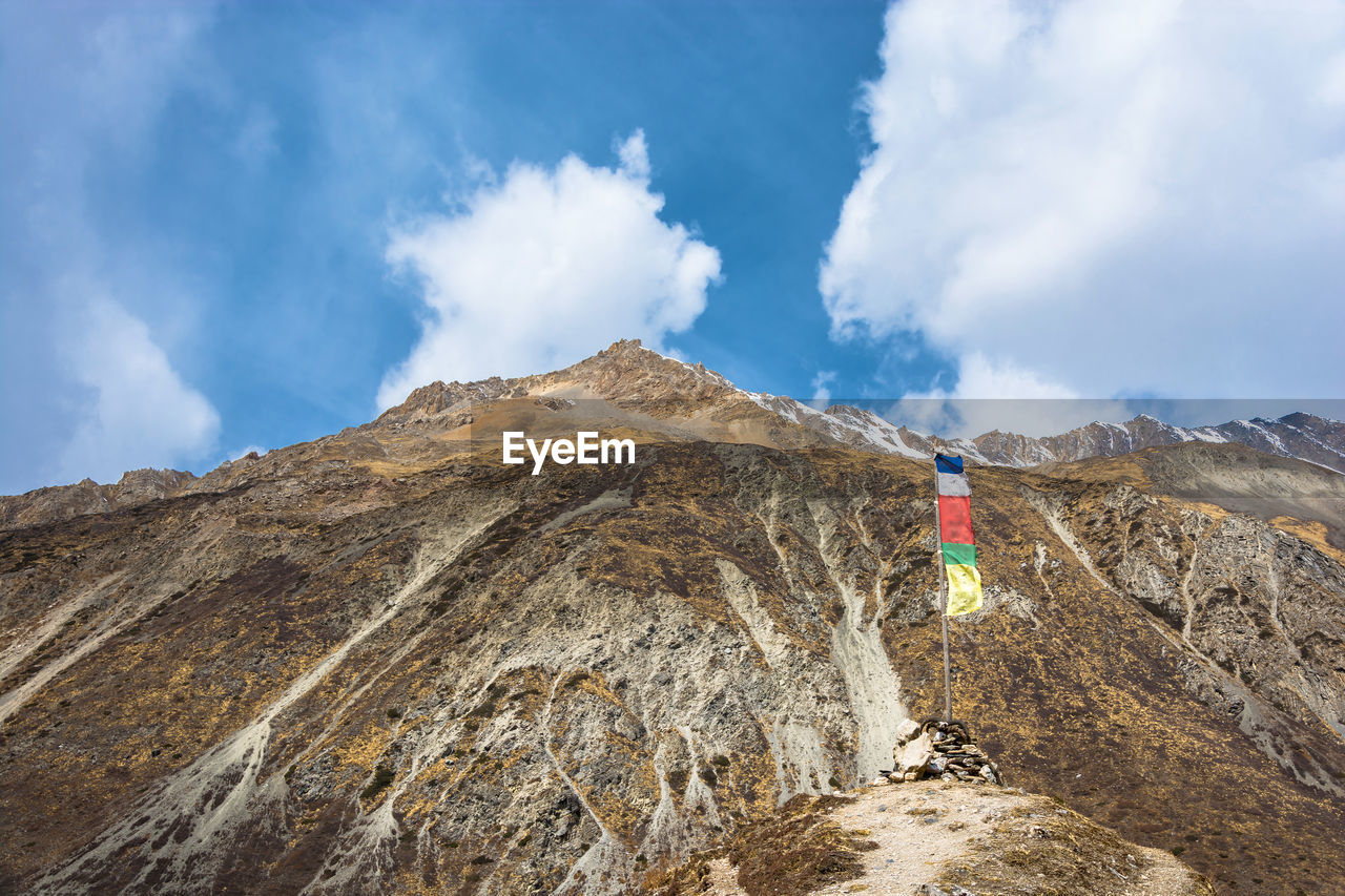 Prayer flags on rocky mountains against sky