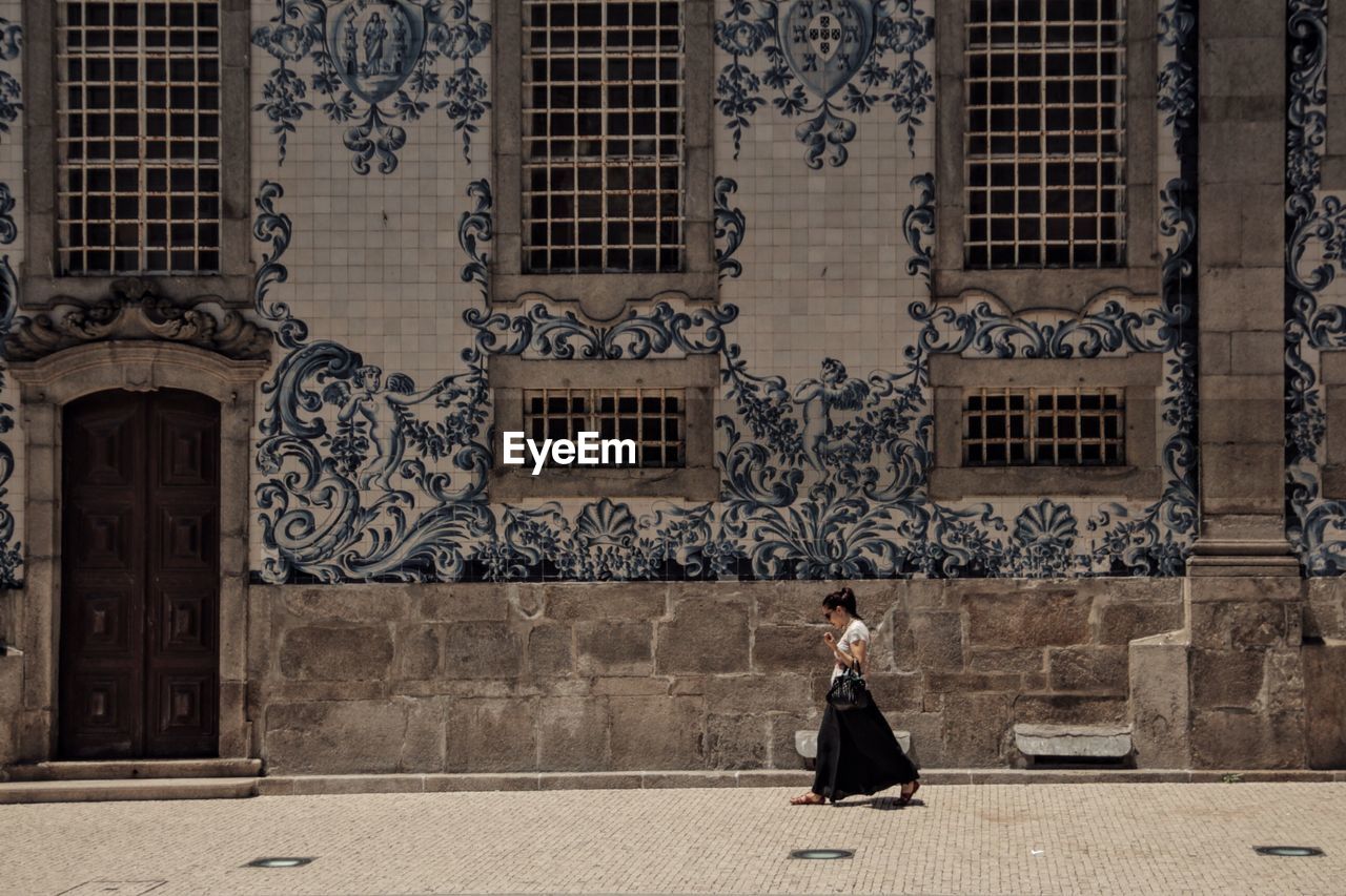 WOMAN STANDING IN FRONT OF BUILDING