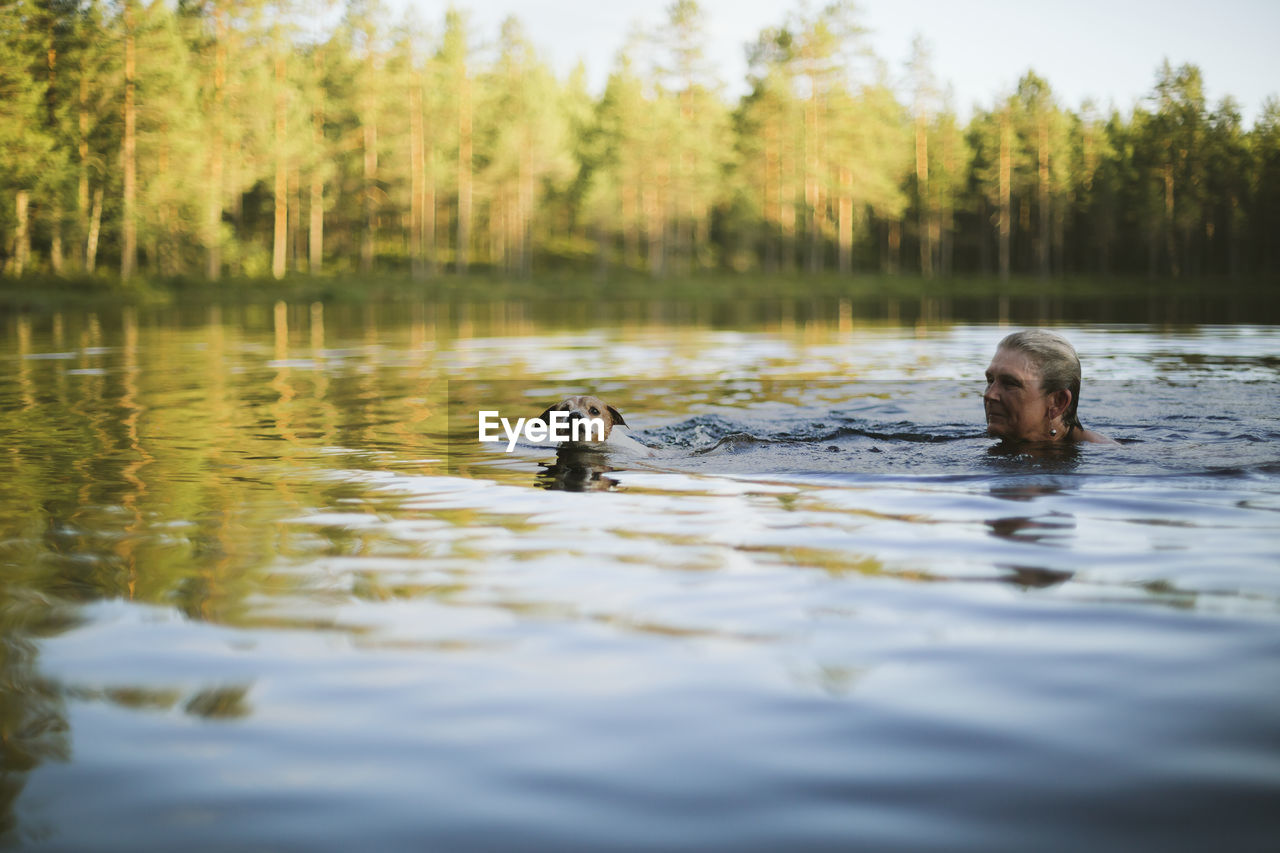 Woman with dog swimming in lake