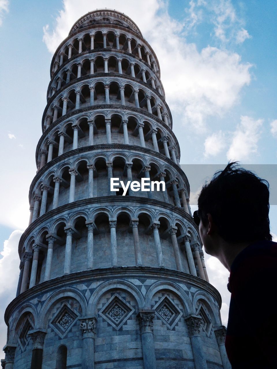 Low angle view of man standing by leaning tower of pisa