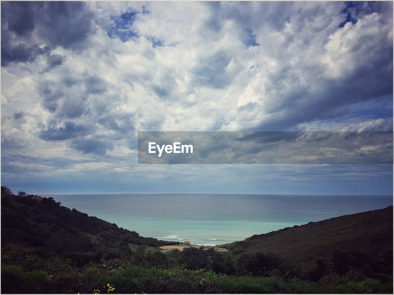 Scenic view of sea and mountains against cloudy sky