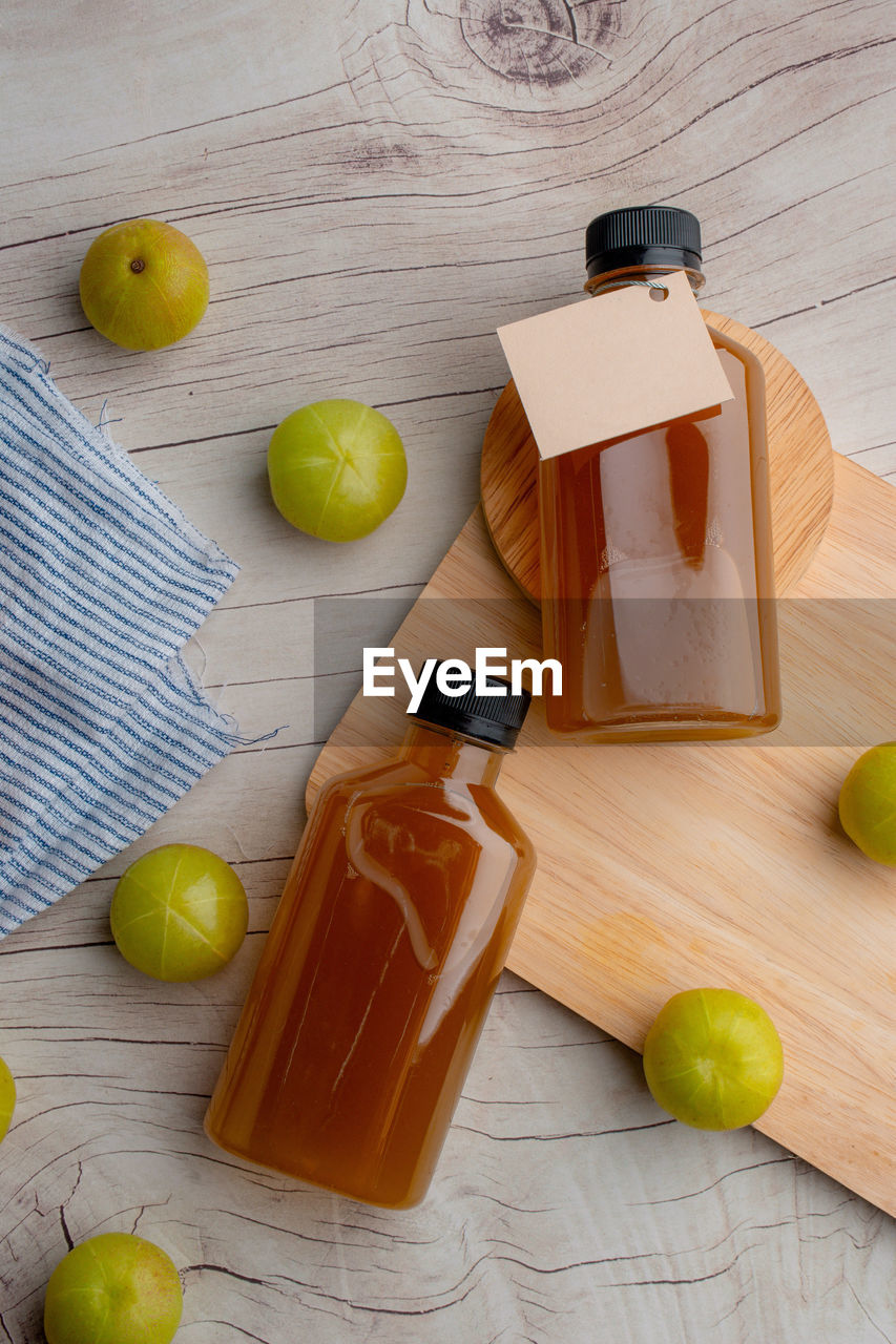 Ayurvedic amla or indian gooseberry juice in a bottle, healthy diet on wooden basket on wood table 