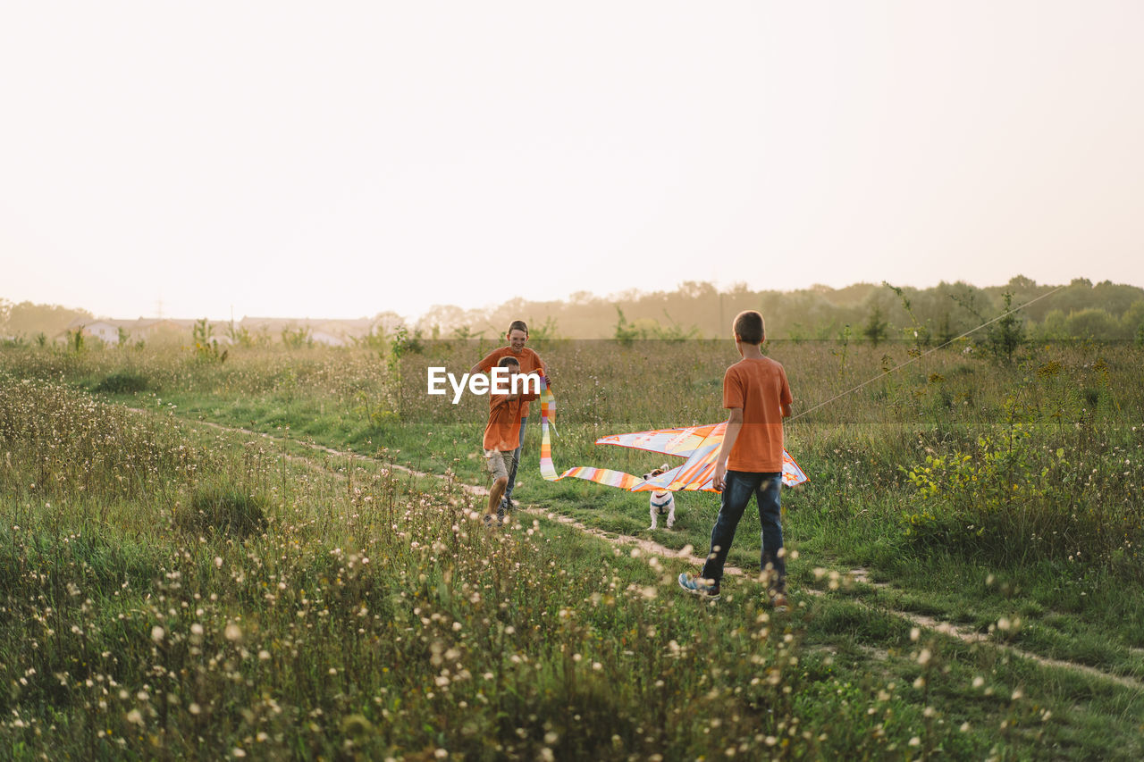 Happy family and children run on meadow with a kite in the summer on the nature.