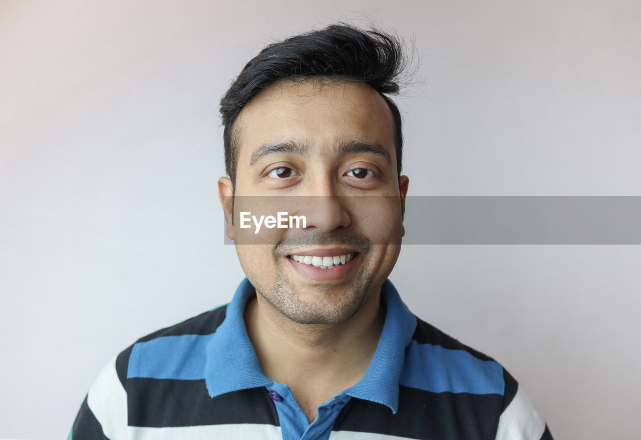 PORTRAIT OF YOUNG MAN AGAINST GRAY BACKGROUND