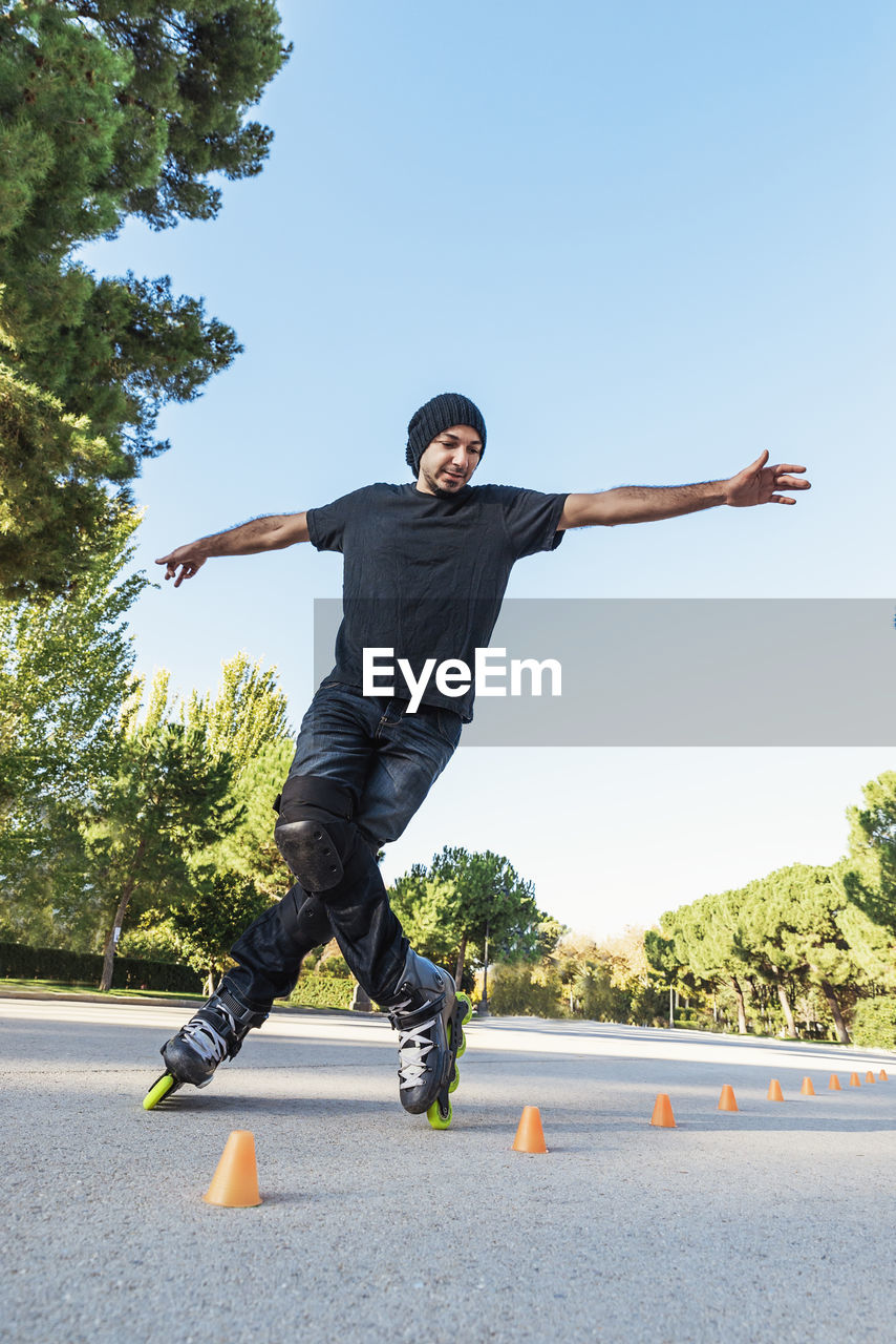 Low angle view of man skating on road against clear sky