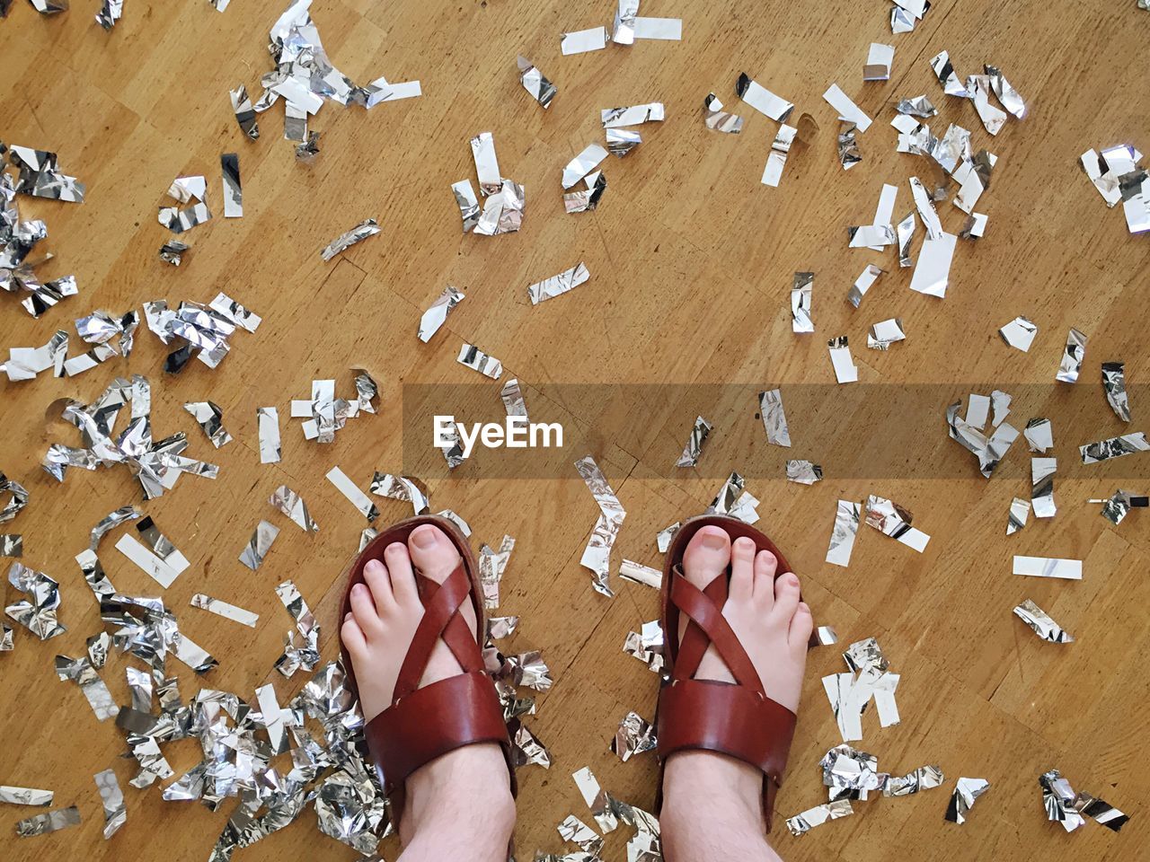 Low section of person standing amidst confetti on floor