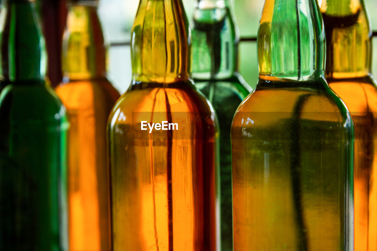 CLOSE-UP OF GLASS BOTTLES ON SHELF