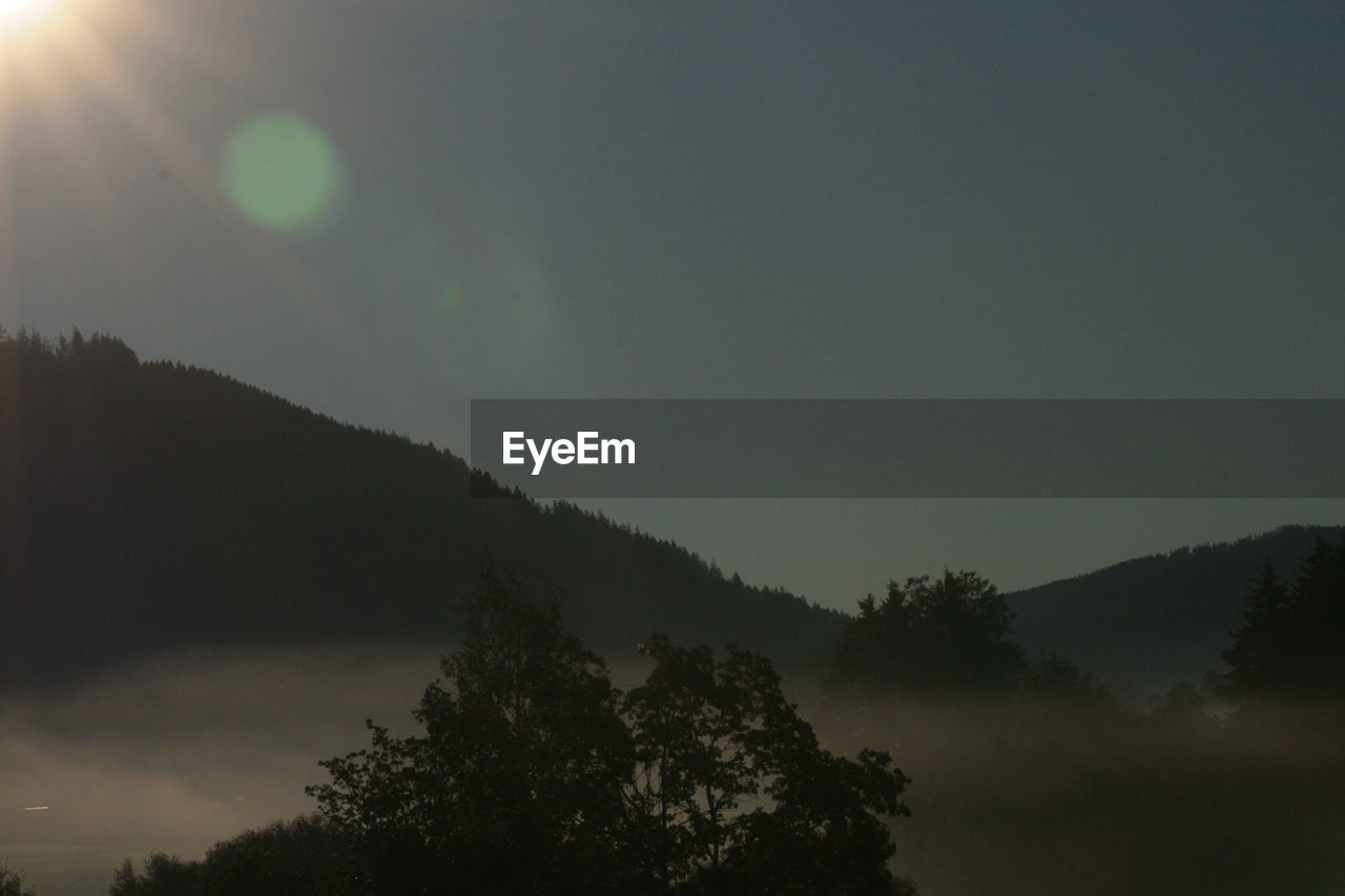 Low angle view of silhouette trees and mountain against sky during sunset