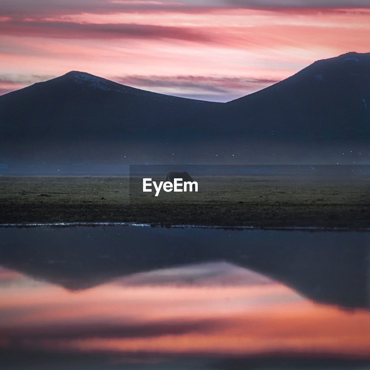 Scenic view of lake against mountains during sunset