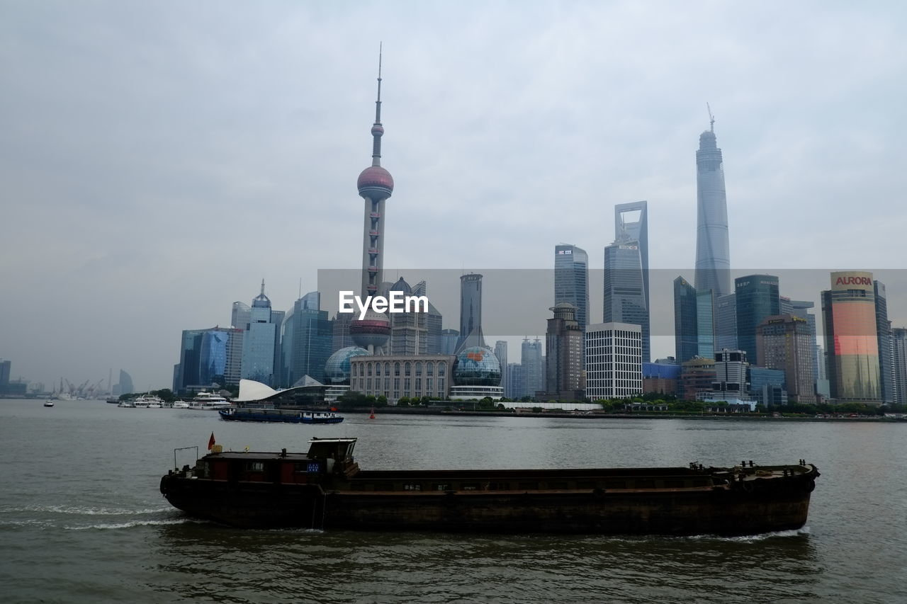 Boat sailing on river against shanghai world financial center in city