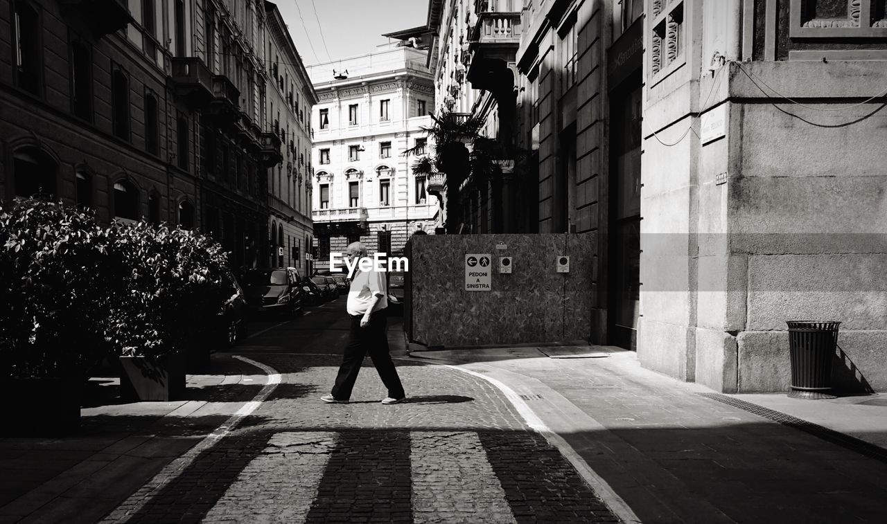 REAR VIEW OF WOMAN WALKING ON CITY STREET