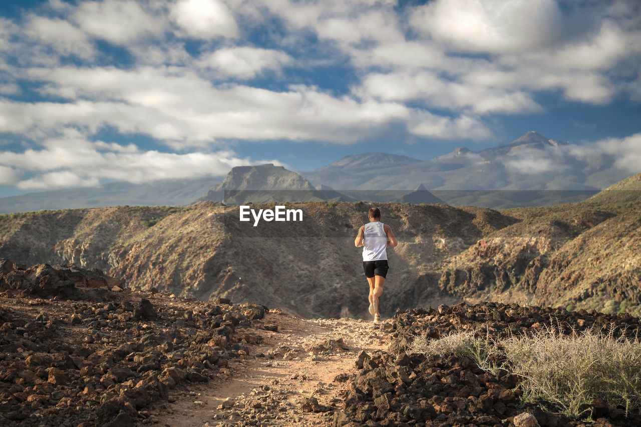 Rear view of man running on mountain against sky