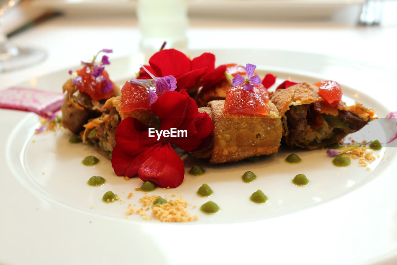 Close-up of flowers on spring rolls with meat in plate