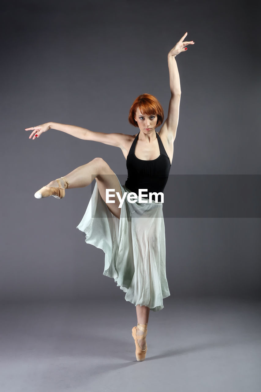 Portrait of ballet dancer dancing against gray background