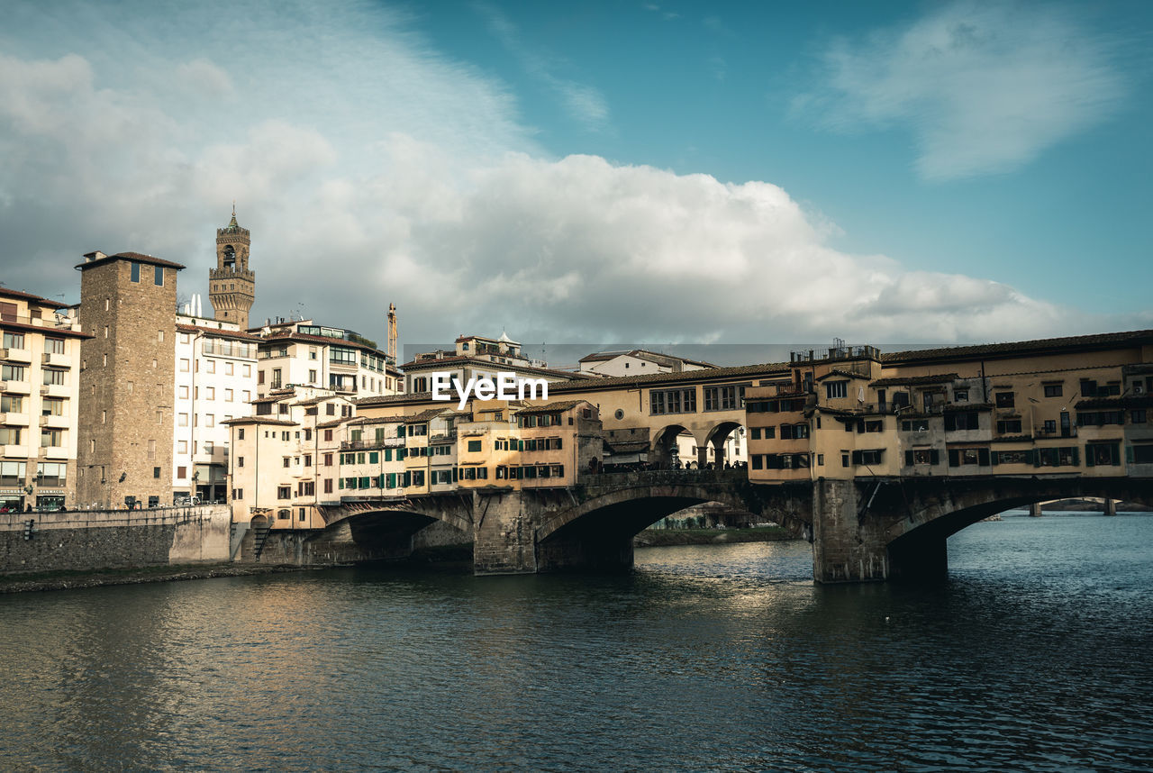 ARCH BRIDGE OVER RIVER AGAINST BUILDINGS IN CITY