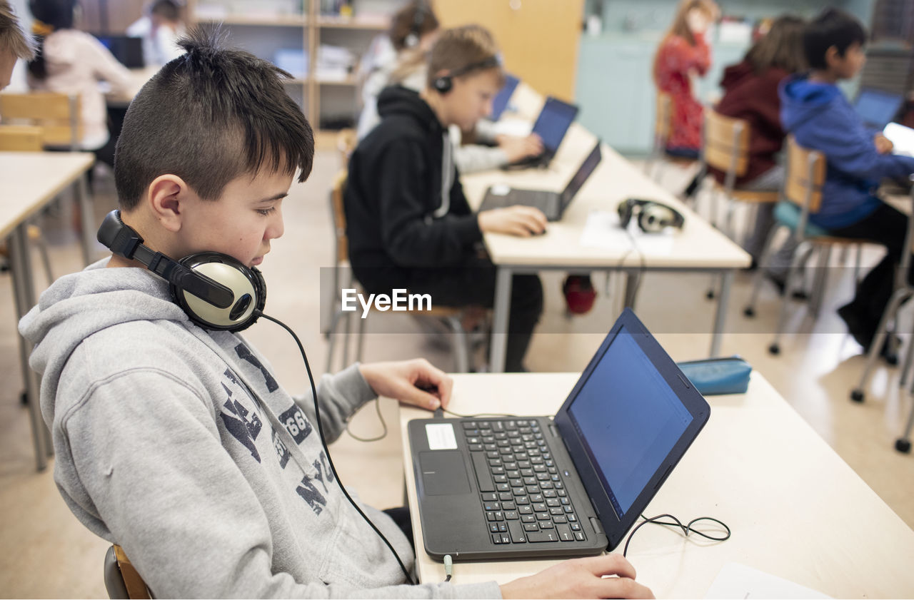 Boy in classroom using laptop