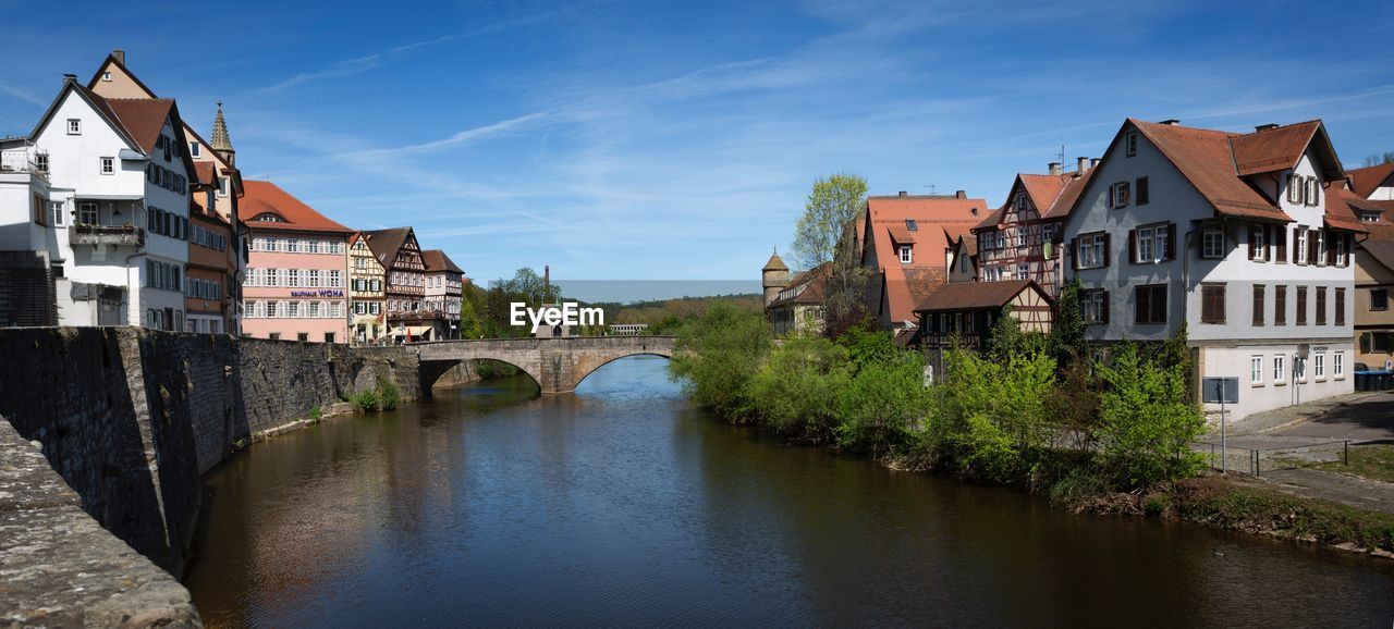 Bridge over river amidst buildings in city against sky