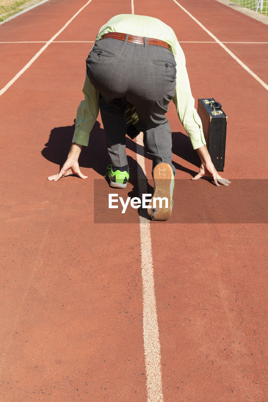 Rear view of businessman with suitcase on running track