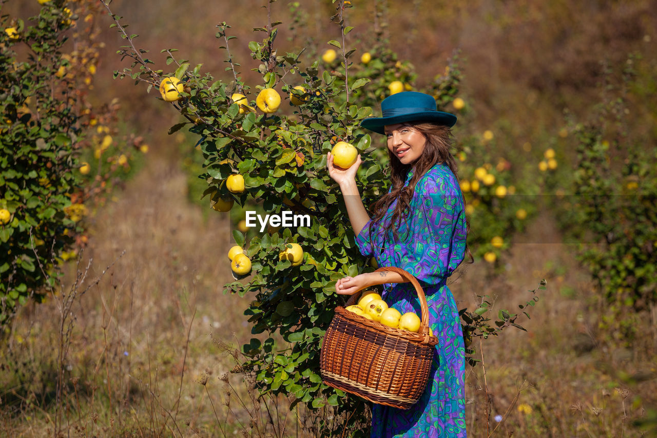 Portrait of woman picking fruits from plants