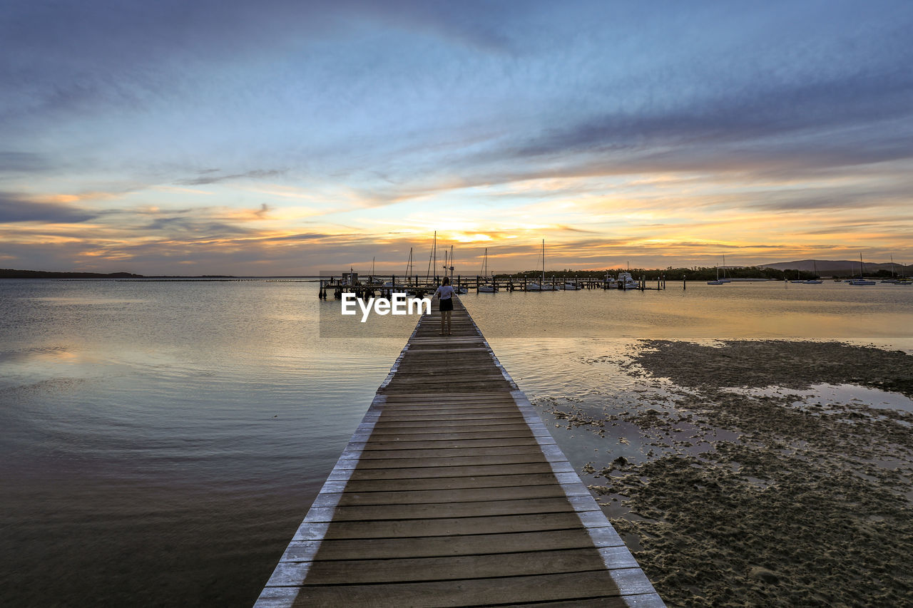 Pier over sea against sky during sunset